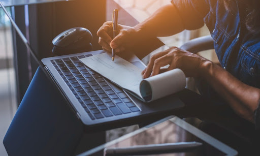 A business owner writing a payroll check sitting at a desk.