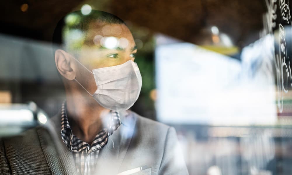 a man with reentry anxiety wearing a mask and looking out a window